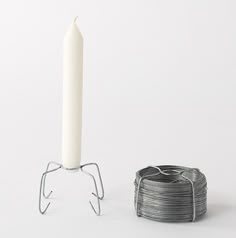 a single white candle sitting next to a stack of coils