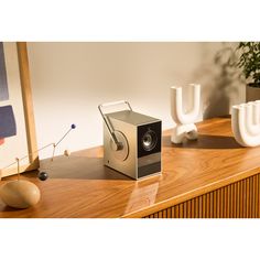 an electronic device sitting on top of a wooden table next to vases and plants