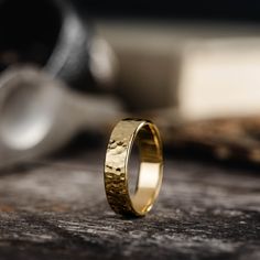 a gold wedding ring sitting on top of a wooden table