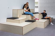 three people sitting on some steps with skateboards