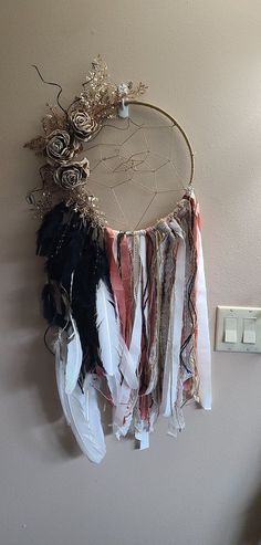 a dream catcher hanging on the wall with feathers