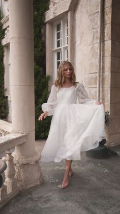 a woman in a white dress is standing outside