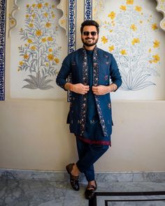 a man standing in front of a wall with yellow flowers on it's side