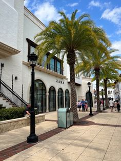 palm trees line the sidewalk in front of a building