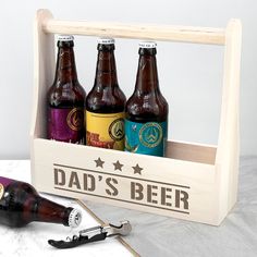 three bottles of beer in a wooden crate with a corkscrew and bottle opener