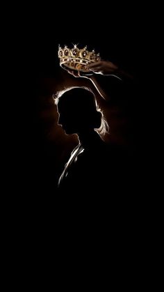 the silhouette of a person with a crown on their head, against a black background