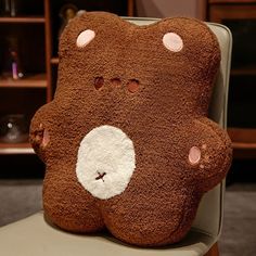 a brown teddy bear pillow sitting on top of a chair