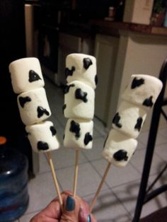 marshmallows with black and white spots on them are being held by someone's hand