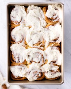 a pan filled with cinnamon rolls covered in icing