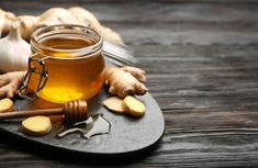 a glass jar filled with honey sitting on top of a table next to sliced ginger