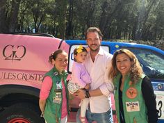 a man and two women holding a baby in front of a truck