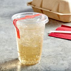 a plastic cup filled with liquid sitting on top of a table next to a container