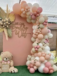 a teddy bear sitting next to a giant balloon arch