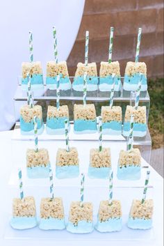 there are many desserts on the table with blue and green straw sticks sticking out of them