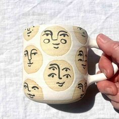 a hand holding a coffee mug with faces on it