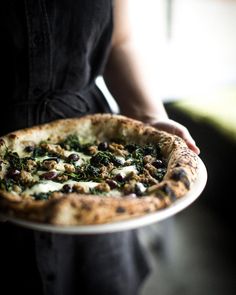 a person holding a plate with a pizza on it