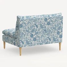 an upholstered blue and white floral print couch with wooden legs, against a white background