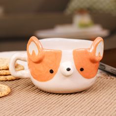 a ceramic cup with a corgi face on it and crackers next to it