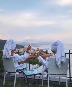 two women in robes sitting on white chairs