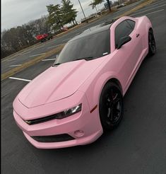 a pink chevrolet camaro parked in a parking lot