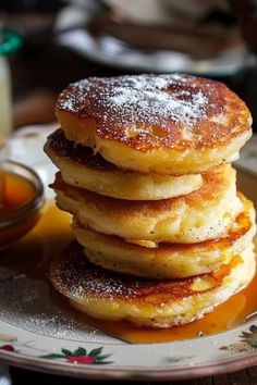 a stack of pancakes sitting on top of a plate covered in powdered sugar and syrup