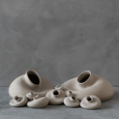 a group of white vases sitting on top of a cement floor next to each other