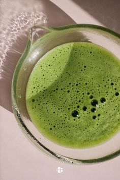 a green drink in a glass on top of a table