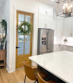 a kitchen with white counter tops and wooden chairs