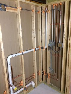 an unfinished room with pipes and piping in the wall next to toilet paper rollers