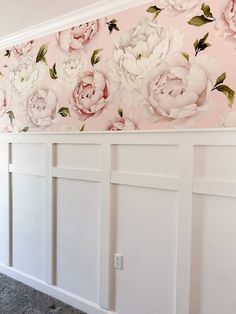 a wall with flowers painted on it and white paneling in front of the door