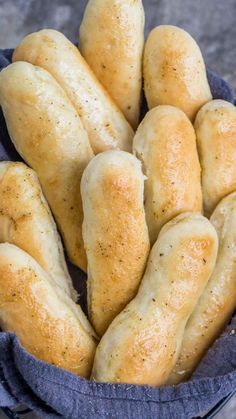 breadsticks in a basket on a table with a blue cloth around them and sprinkled with seasoning