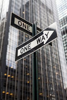 one way and one way street signs in front of skyscrapers