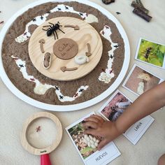 a child's hand is touching a wooden plate with pictures and magnets on it