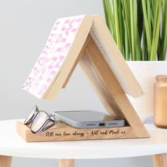 a wooden stand with a cell phone and sunglasses on it next to a potted plant