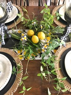 the table is set with black and white plates, napkins, and lemons