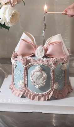 a cake that has been decorated with pink and blue designs on it, as well as a candle