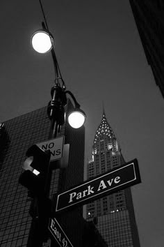 black and white photograph of street signs in new york city with skyscrapers in the background