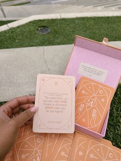 a person holding an orange and pink card in front of some cards on the ground