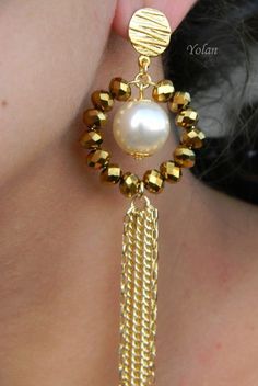 a close up of a person wearing gold earrings with pearls and beads on it's ear