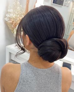 a woman with her hair in a low bun is looking at herself in the mirror