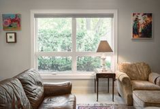 a living room with two couches and a lamp in front of a large window