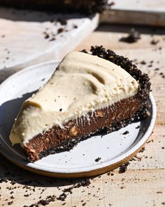 a piece of chocolate pie on a white plate with some dirt around it and one slice missing