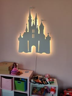 a castle shaped light is on the wall above a book shelf and toy bins