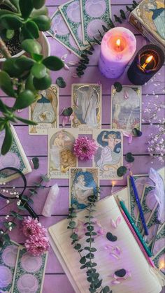 a table topped with cards and flowers next to a candle