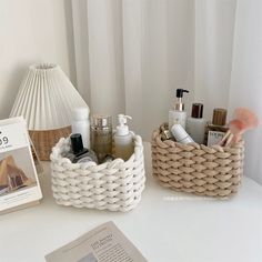 a white table topped with baskets filled with cosmetics and personal care items next to a book