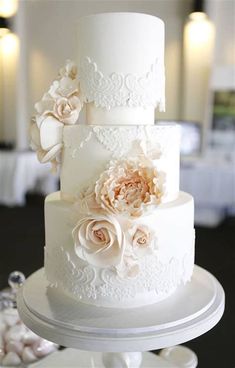 a three tiered white wedding cake with flowers on top