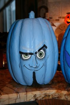 two blue pumpkins with faces painted on them sitting on a counter in a kitchen