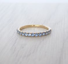 a yellow gold band with blue topaz stones on the side, sitting on a white surface