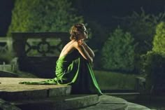 a woman in a green dress sitting on steps