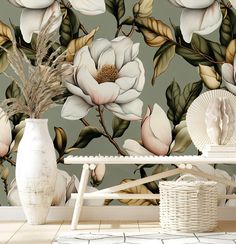 a white vase sitting on top of a table next to a flower wallpaper mural